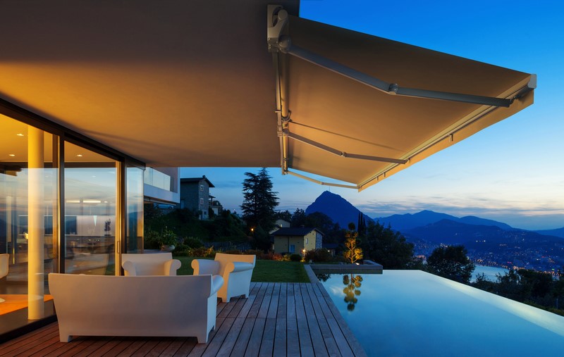 Toldo de brazo extensible sobre una terraza con piscina al atardecer, instalado por Sombras Osiris